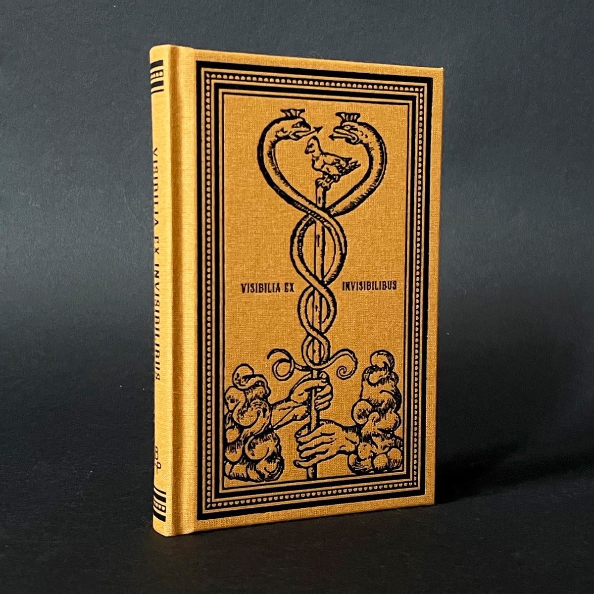 A cloth-bound notebook with a printer's mark on the cover, featuring gothic-style lettering and illustrations.