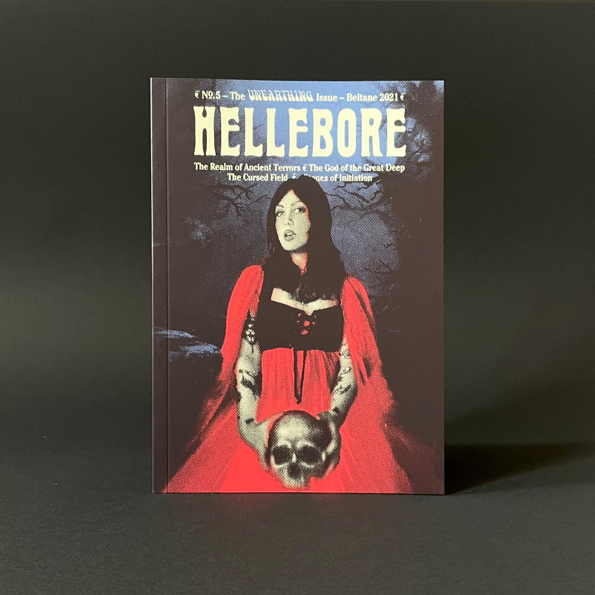 Book titled 'Hellebore' with a dark cover featuring a woman in a red cloak and skull.