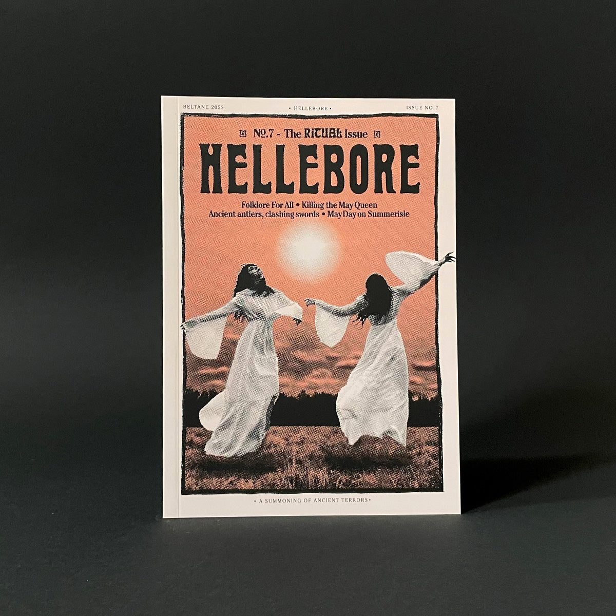 Magazine cover titled 'Hellebore' with two women in white dresses against a sunset sky.