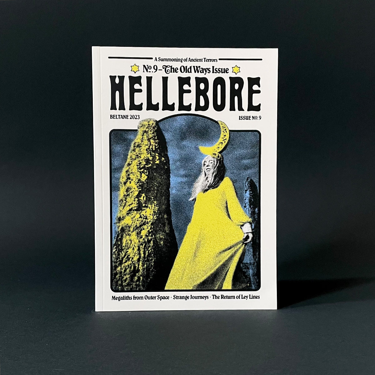 Magazine cover titled 'Hellebore' with a person in a yellow robe and moon helmet against a dark background.