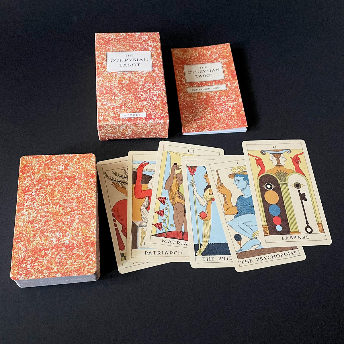 Otheysian Tarot cards with red marbled covers on a black background