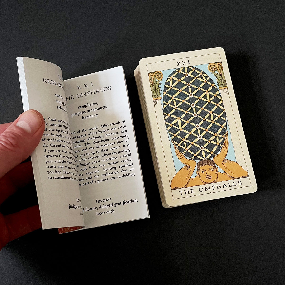 Card with 'The Omphalos' design and open book on a black background