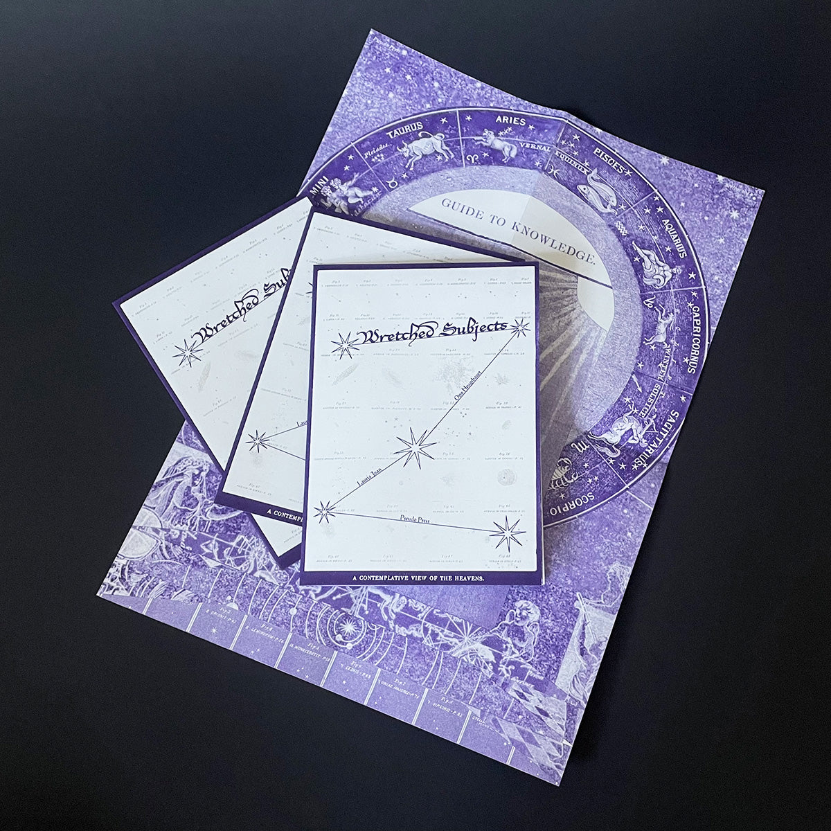 A5 folded zine titled 'Wretched Subjects', riso printed with purple and metallic gold ink, with a poster on the reverse, displayed on a dark background.