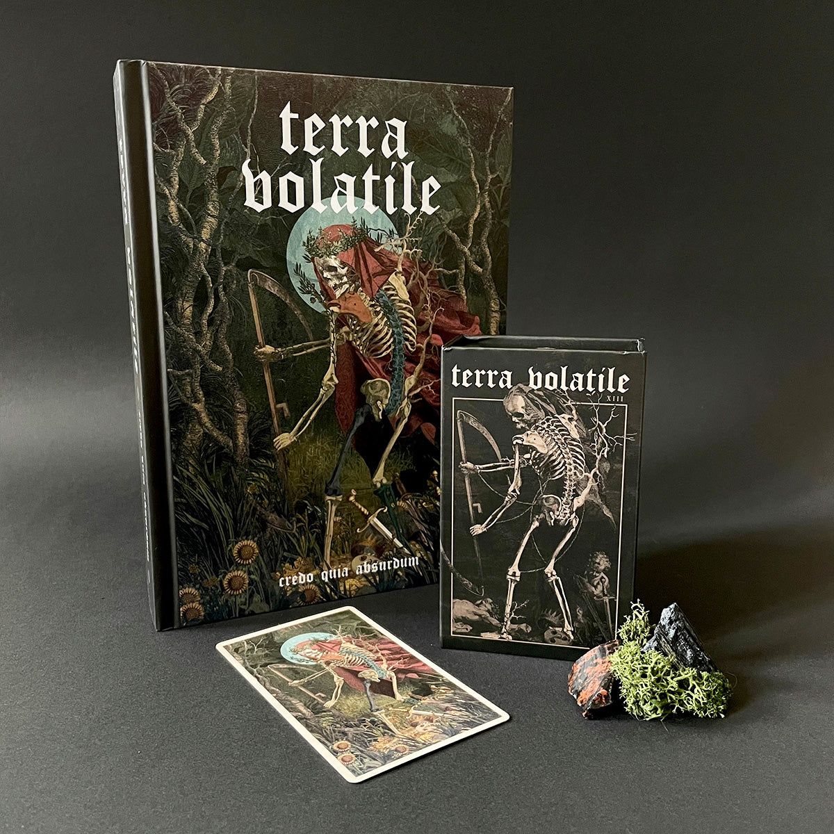 Terra Volatile book, tarot card, and box on a dark surface