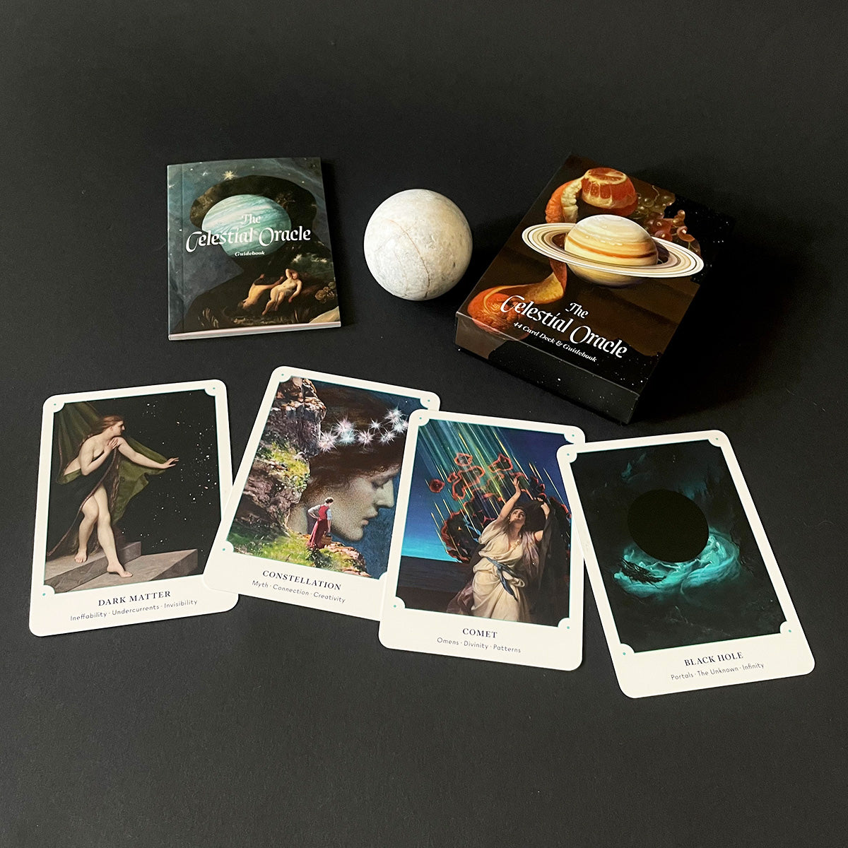 Set of oracle cards titled 'Celestial Oracle' on a dark surface with packaging and a moonstone.