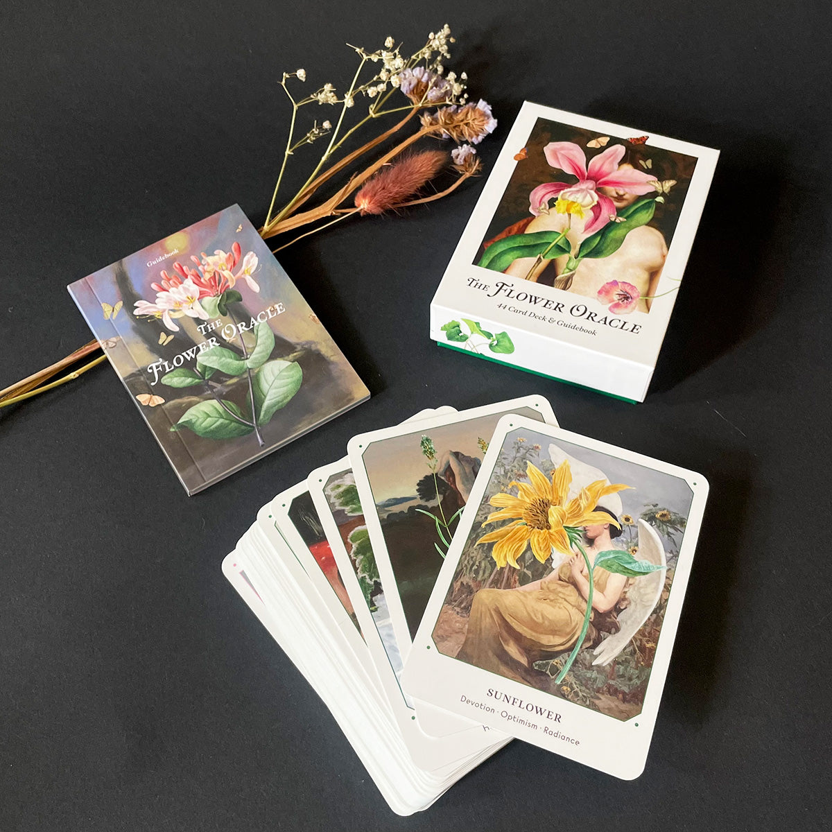 Flower Oracle cards on a dark surface with dried flowers.