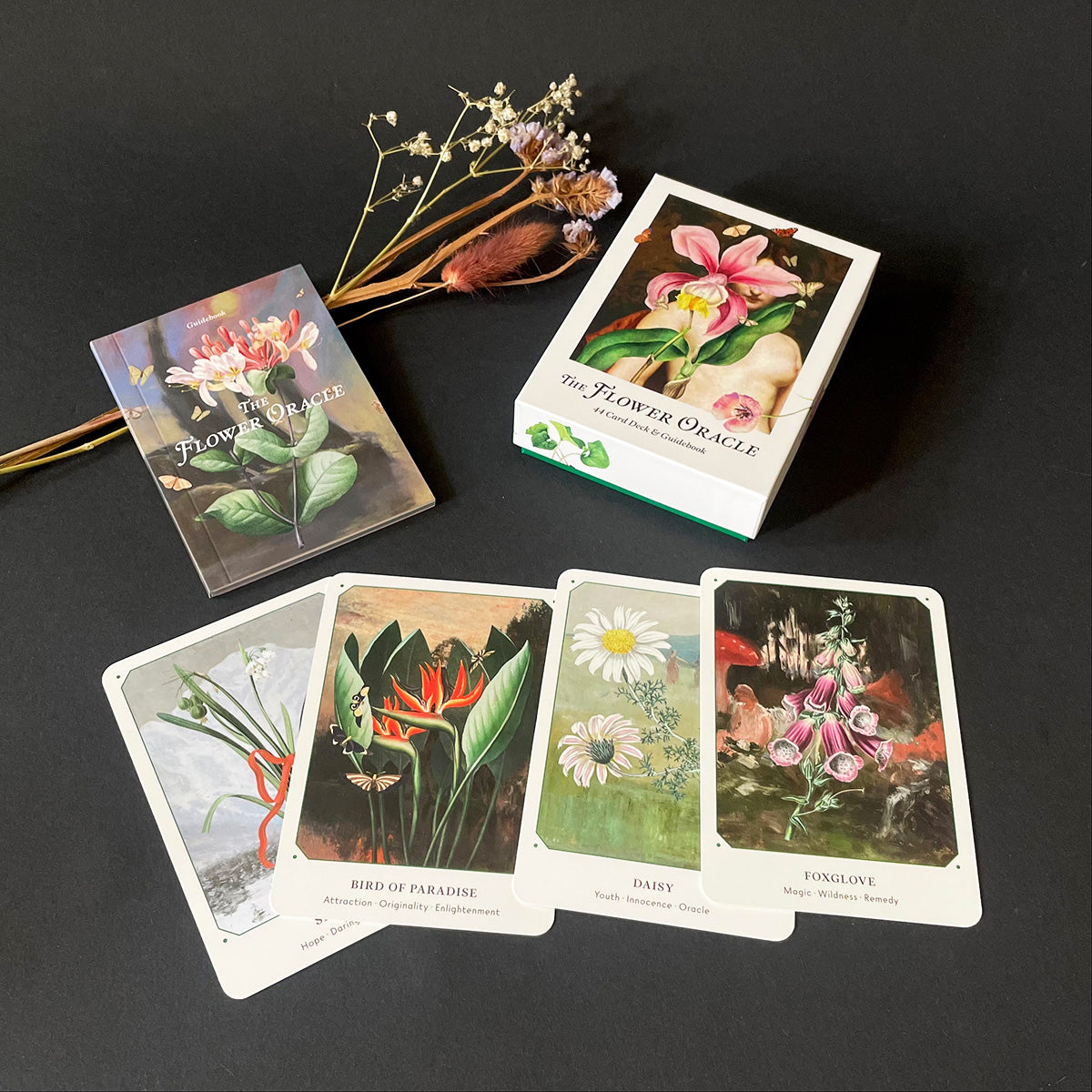 Flower Oracle cards on a dark surface with dried flowers.