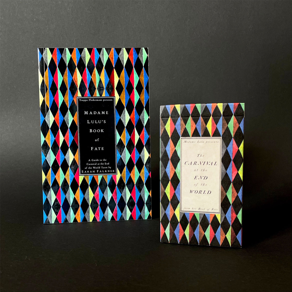The image shows a deck of tarot cards and guidebook with colorful, geometric patterns. The packaging of the deck features a vibrant, multicolored geometric design, while the book has a more subdued, black and white geometric pattern.