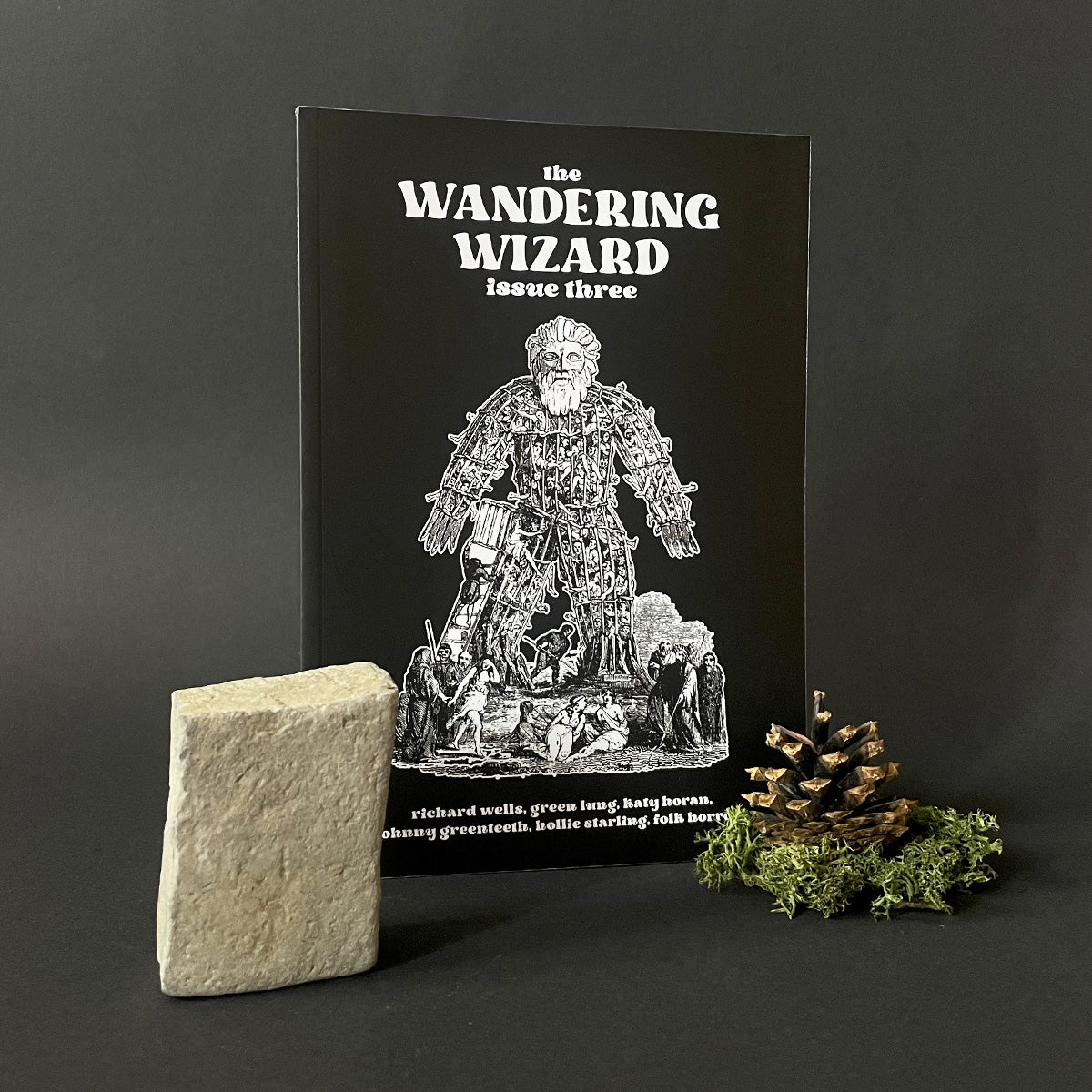 Magazine titled 'The Wandering Wizard Issue Three' with a stone and decorative elements on a dark background