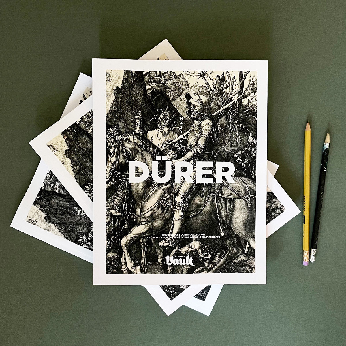 A collection of black and white images of Albrecht Dürer's artwork, with the book 'Dürer' prominently displayed on top, against a dark background. Two pencils are placed to the side.